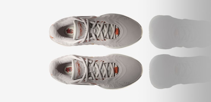 Side view of LeBron James' white and orange Nike basketball shoes.